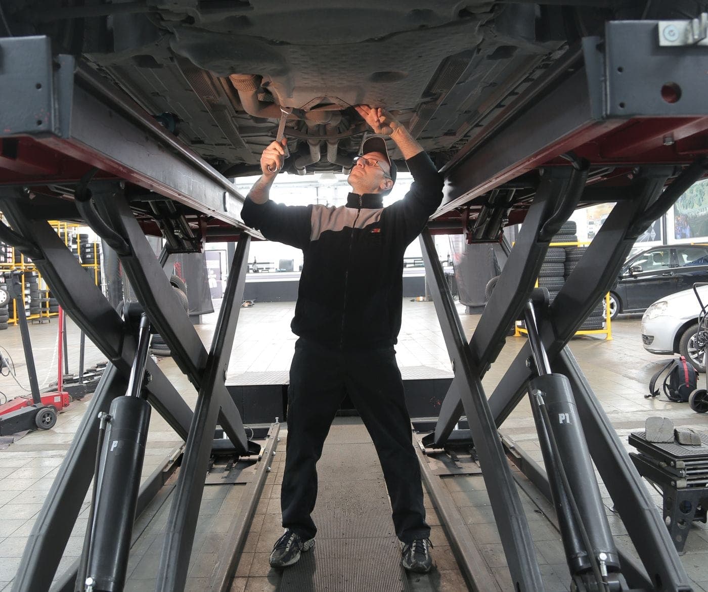 Mechaniker arbeitet unter einem Auto auf der Hebebühne